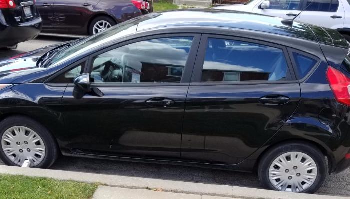 Side view of a black hatchback car parked along a street curb.