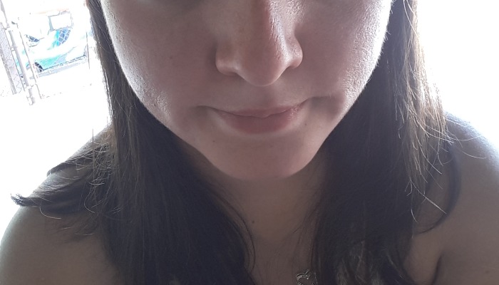 Close-up of a woman with dark hair, a subtle smile, and a heart pendant necklace.