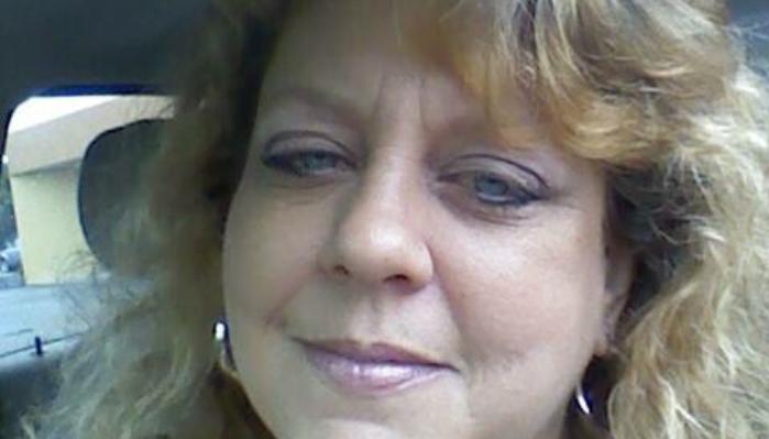 Close-up of a smiling woman with wavy blonde hair and blue eyes inside a car.