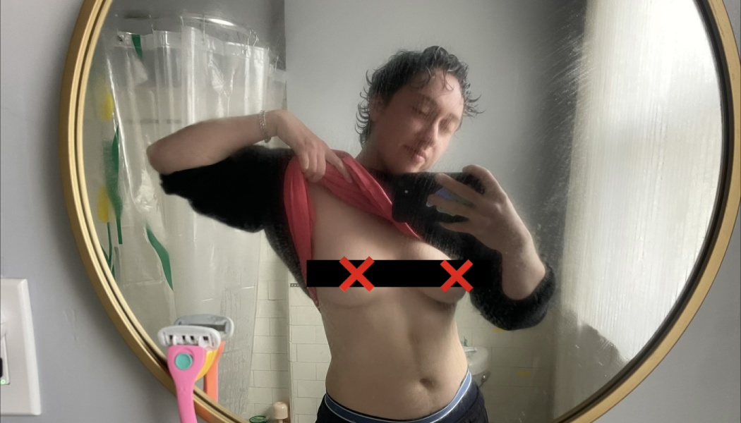 Person lifting their shirt in a round bathroom mirror selfie to show their torso.