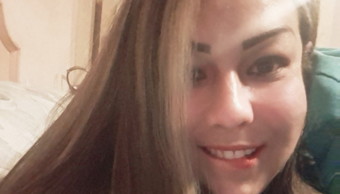 Close-up portrait of a smiling woman with long brown hair looking at the camera.
