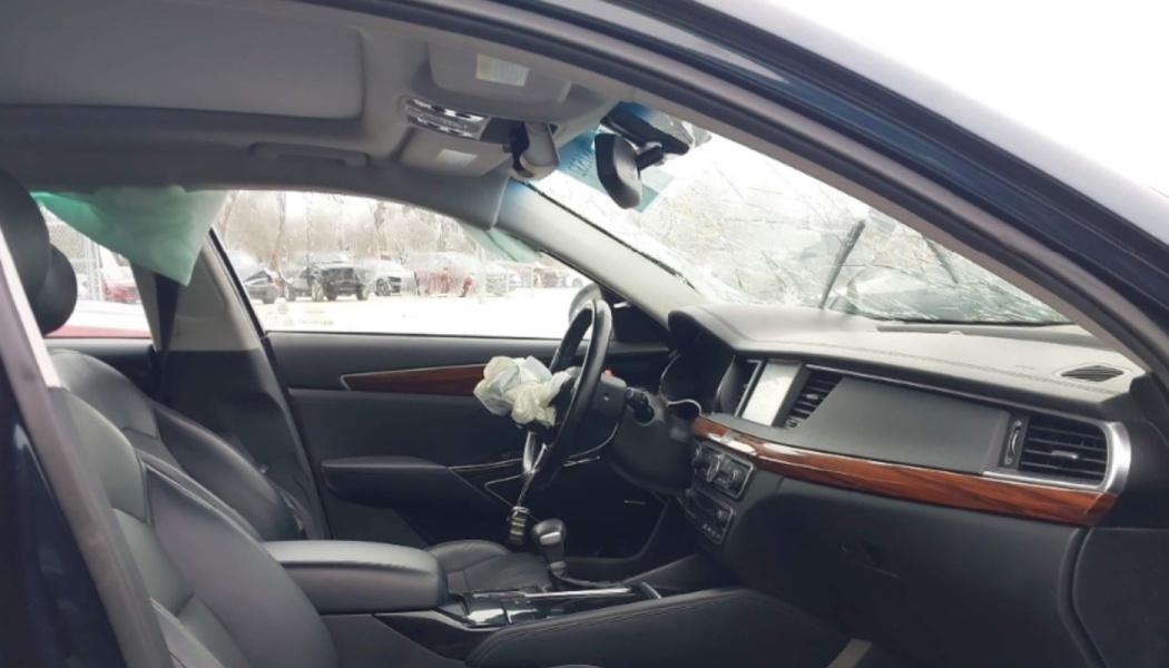 Car interior with a cracked windshield and deployed steering wheel and side curtain airbags.