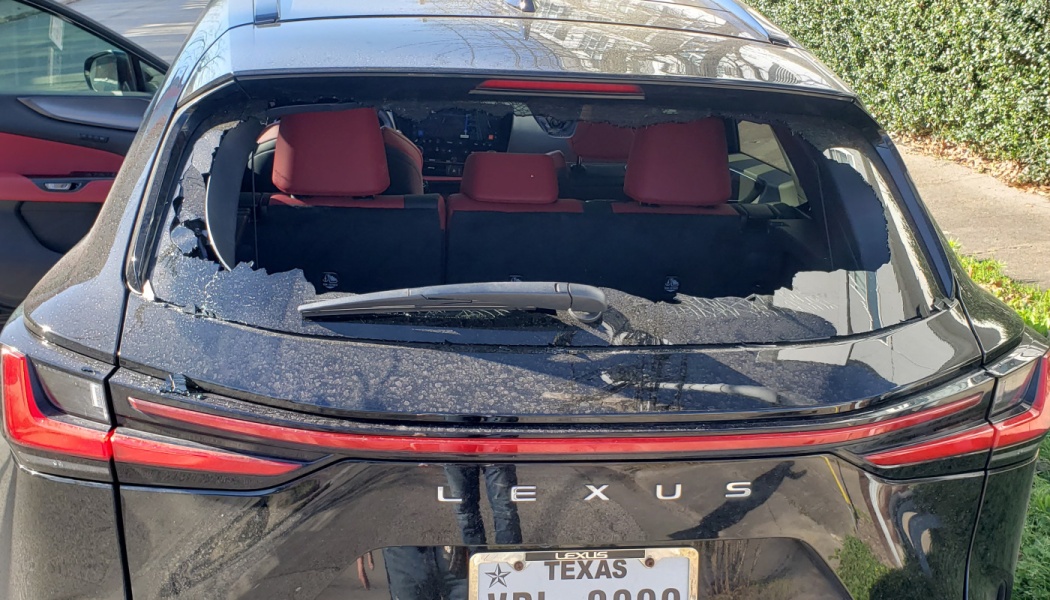 Smashed rear windshield of a black Lexus SUV, revealing red interior seats.