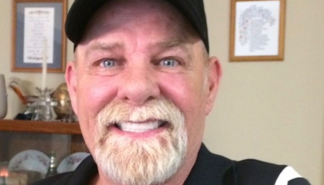 A smiling man with blue eyes, a white goatee, and a black baseball cap.