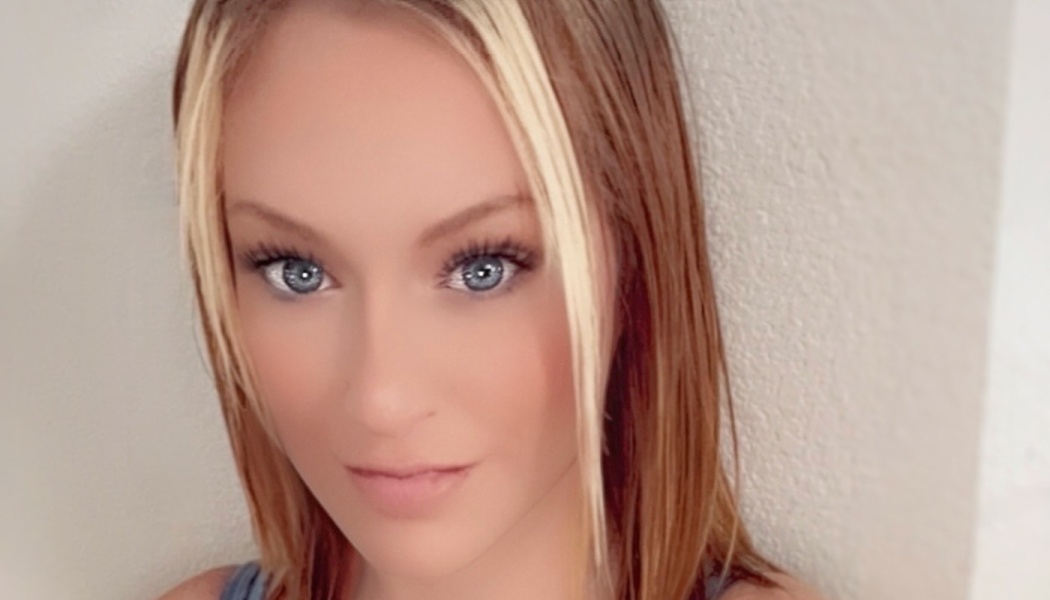 A young woman with striking blue eyes and blonde front highlights framing her light brown hair.