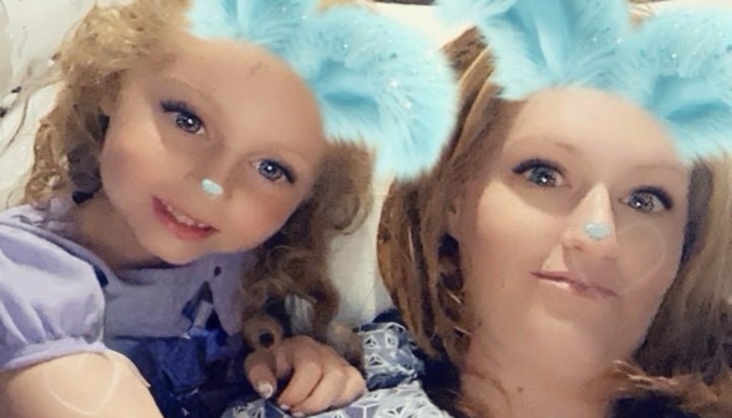 A mother and young daughter smiling together using a playful light blue animal ear digital filter.
