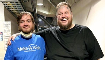 Jelly Roll smiles with his arm around a young man wearing a blue Make-A-Wish shirt backstage.