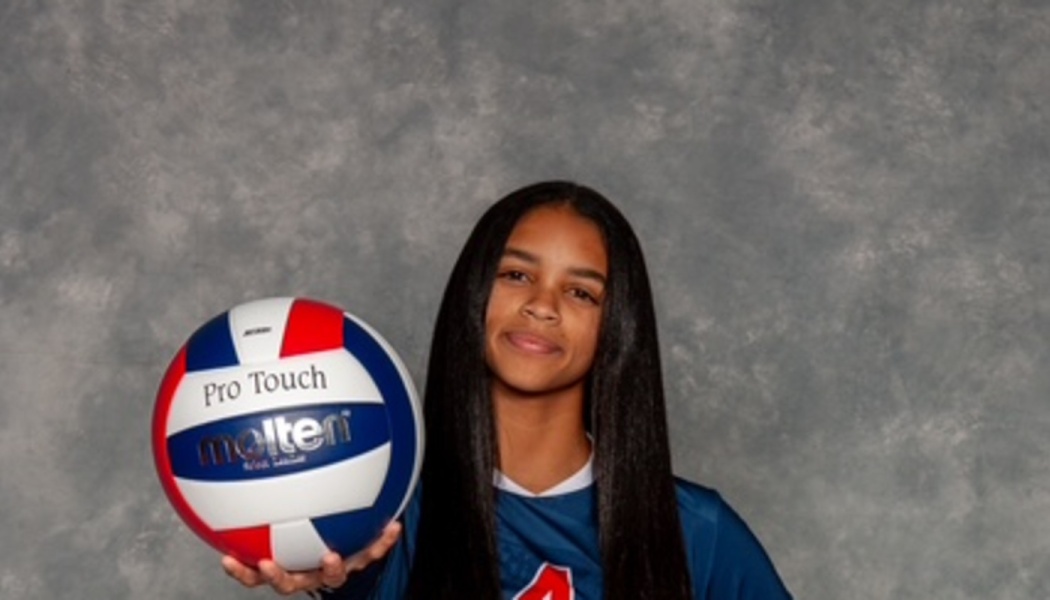 Young female volleyball player with long dark hair holding a Molten volleyball.