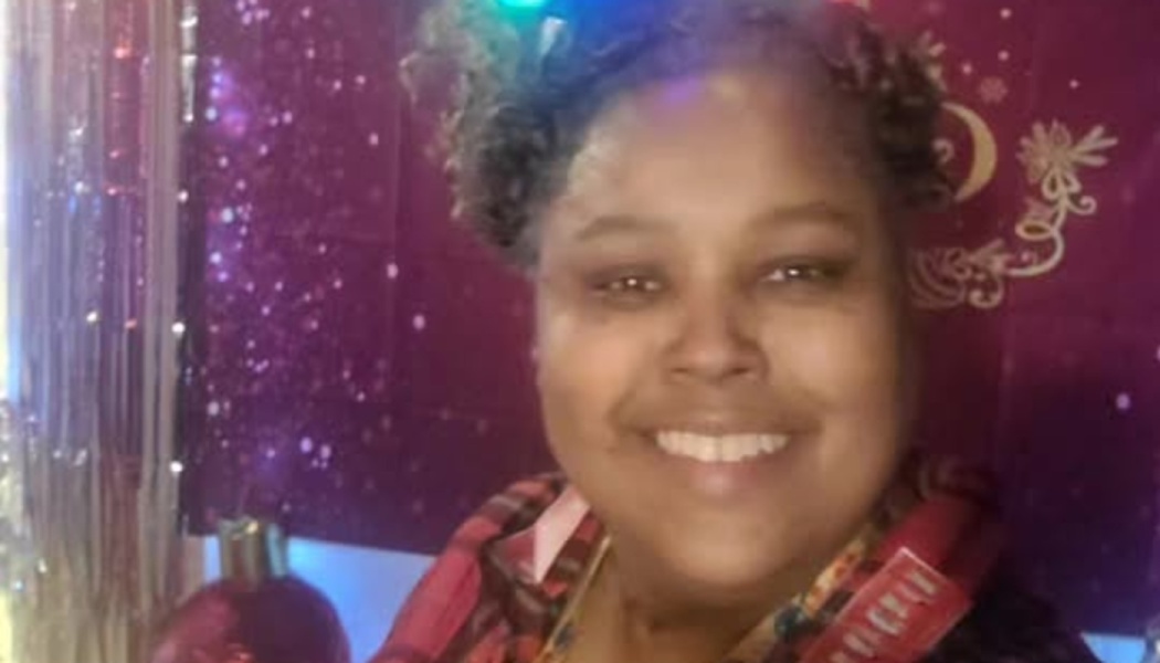 A smiling woman with curly hair in front of a festive, sparkly purple backdrop.
