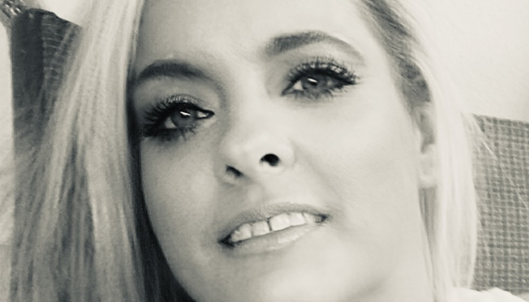 Black and white close-up portrait of a blonde woman smiling slightly at the camera.