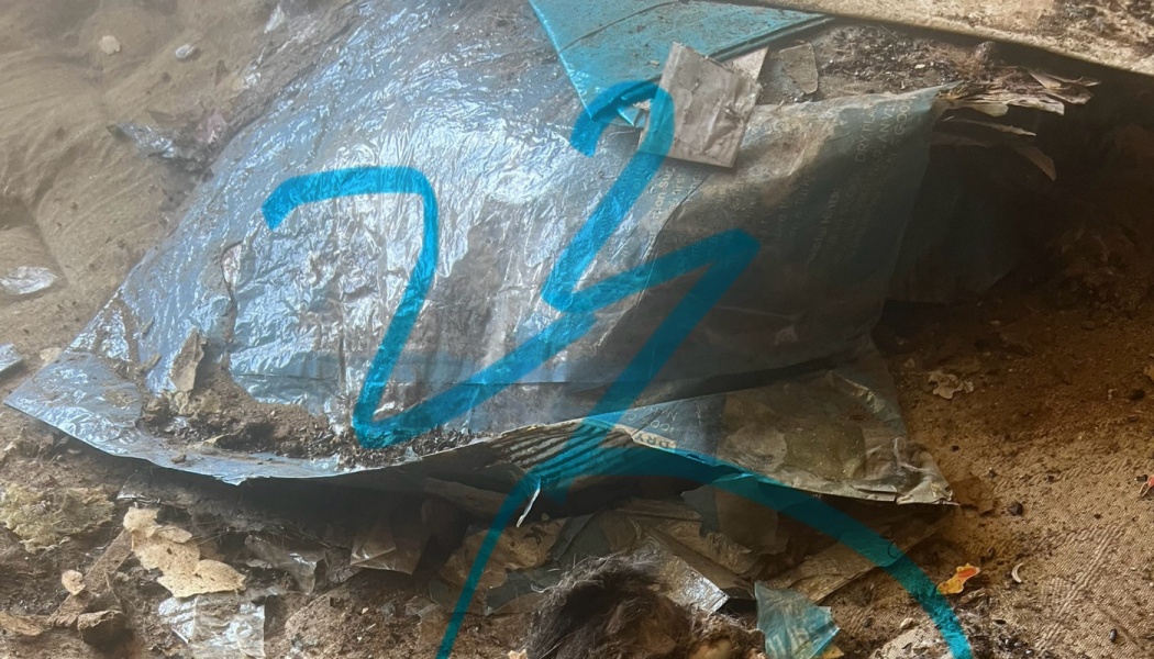 Heavy accumulation of dust, dirt, and torn plastic packaging cluttering a neglected floor.
