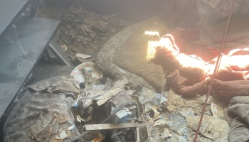 Severely damaged room filled with dust, fallen drywall debris, and ruined household belongings.