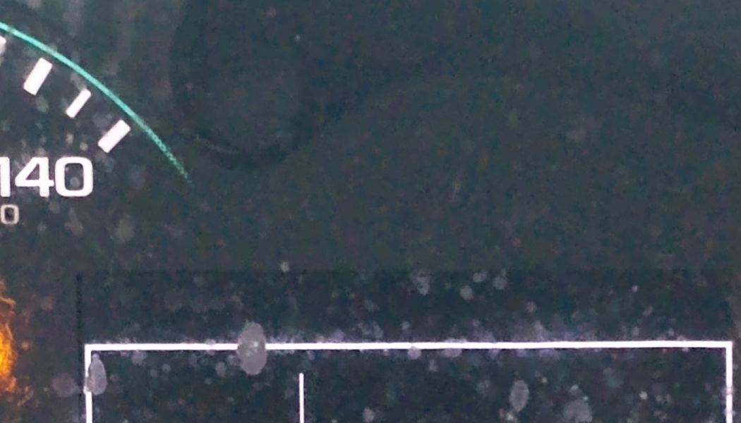 Close-up of a dusty car dashboard display screen showing part of a speedometer reading 140.