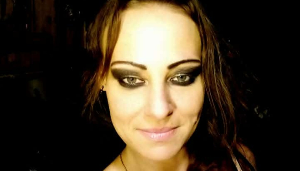 Close-up portrait of a woman with dark hair, heavy smoky eye makeup, and a slight smile.