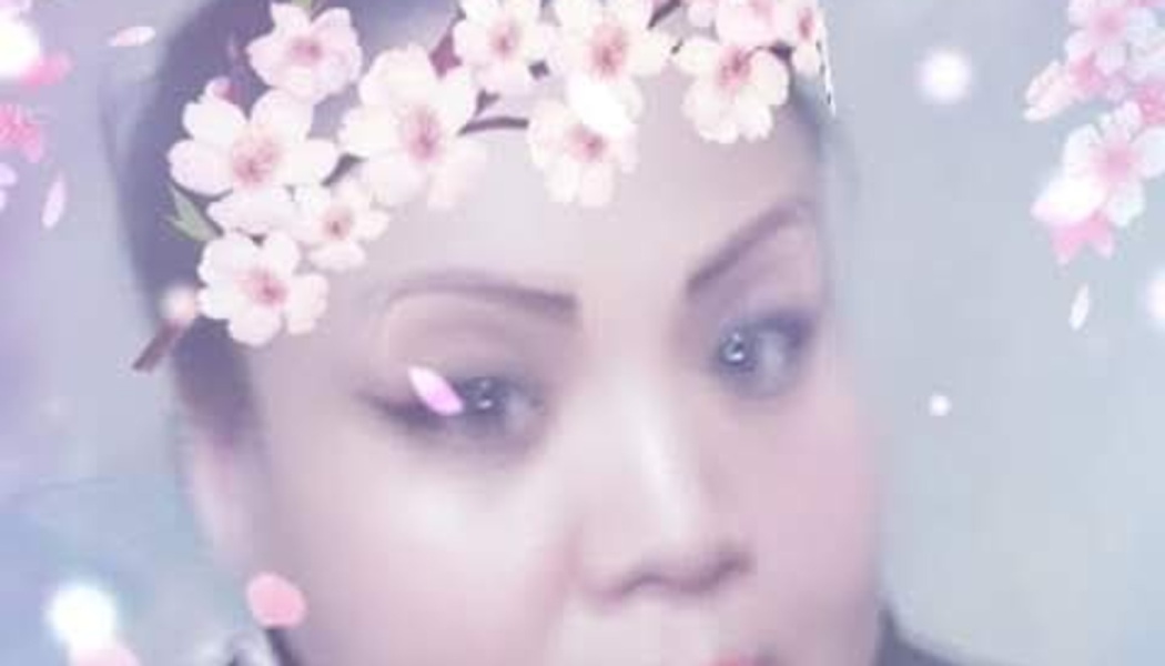 Close-up of a woman with a digital pink cherry blossom crown filter overlay.