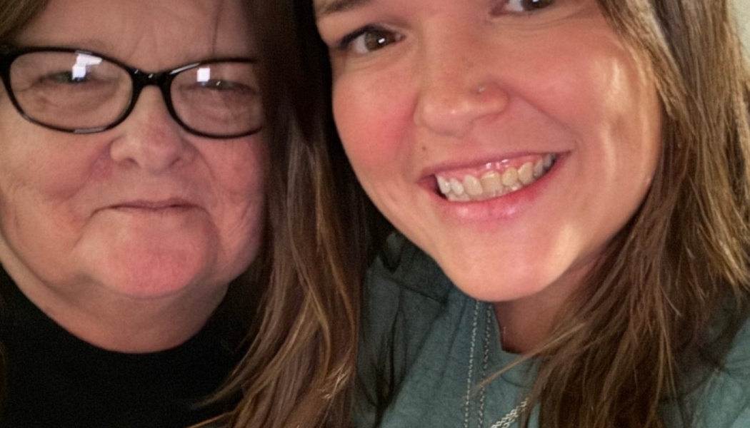 Close-up selfie of an older woman with glasses beside a younger woman smiling broadly.