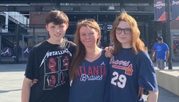 A woman poses with her two teenage children outside a baseball stadium, wearing Atlanta Braves shirts.