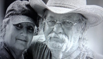 Black and white portrait of a woman in a baseball cap next to a man wearing glasses and a cowboy hat.