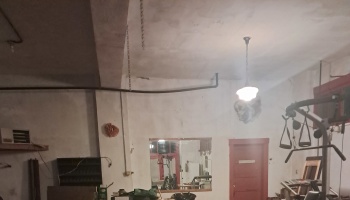 Unfinished indoor gym space with workout equipment, concrete walls, a mirror, and a red door.