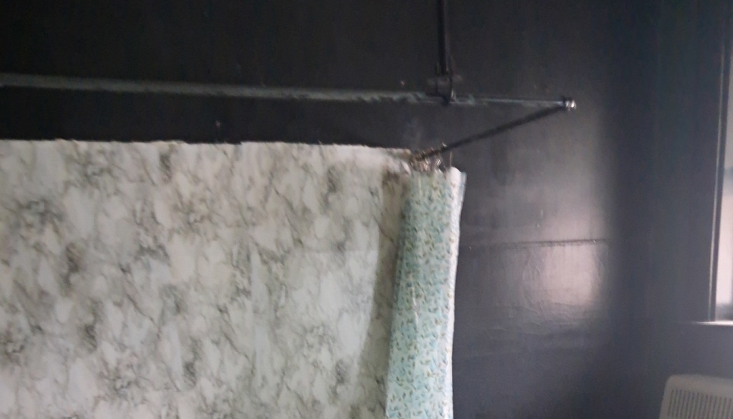 Marble-patterned fabric hanging from a metal rod against a dark wall.