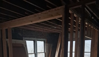 Exposed wooden wall studs and ceiling joists inside a building undergoing renovation.