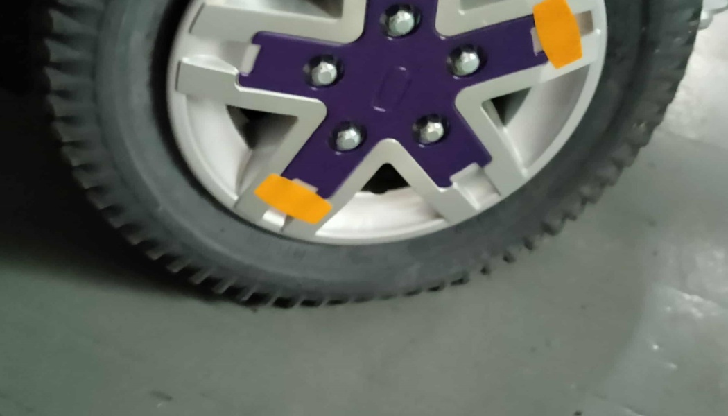 Silver vehicle wheel featuring a purple star-shaped hub trim with bright orange accents.