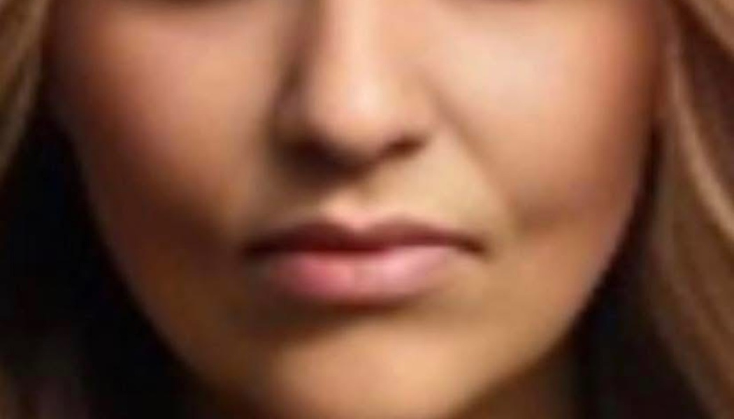 Close-up of a woman's lower face showing her nose, lips, and chin framed by light brown hair.