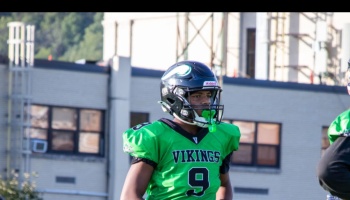 A football player wearing a black helmet and bright green Vikings jersey with number 9.