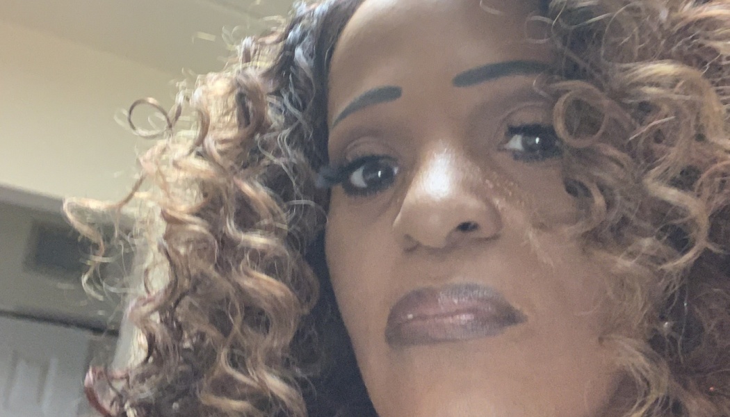 Close-up portrait of a woman with voluminous, curly brown hair framing her face.
