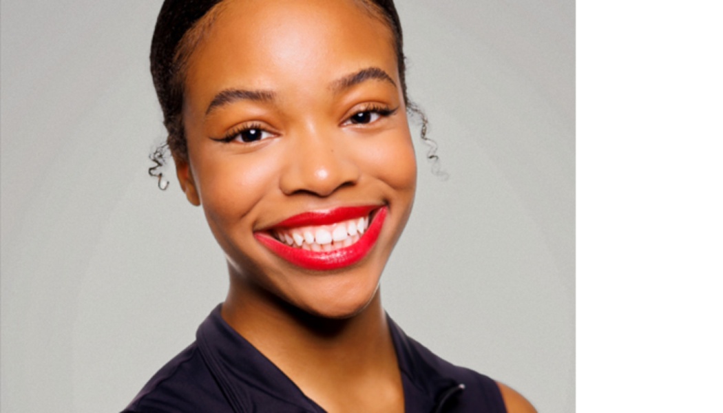 Smiling young Black woman with bright red lipstick and sleek hair pulled back against a neutral background.