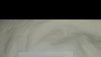 A white paper document with faint text resting on soft, textured off-white fabric.