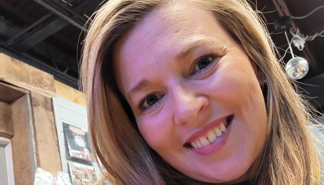 Close-up portrait of a smiling woman with blonde hair looking directly at the camera.