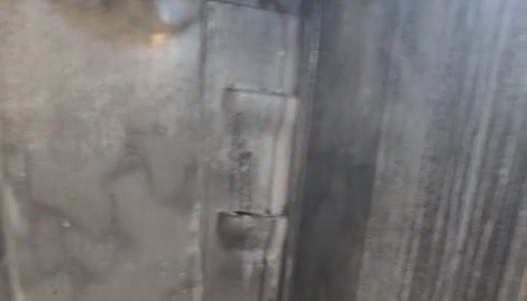Close-up of a heavy metal door hinge on a weathered industrial panel.