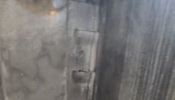 Close-up of a heavy metal door hinge on a weathered industrial panel.