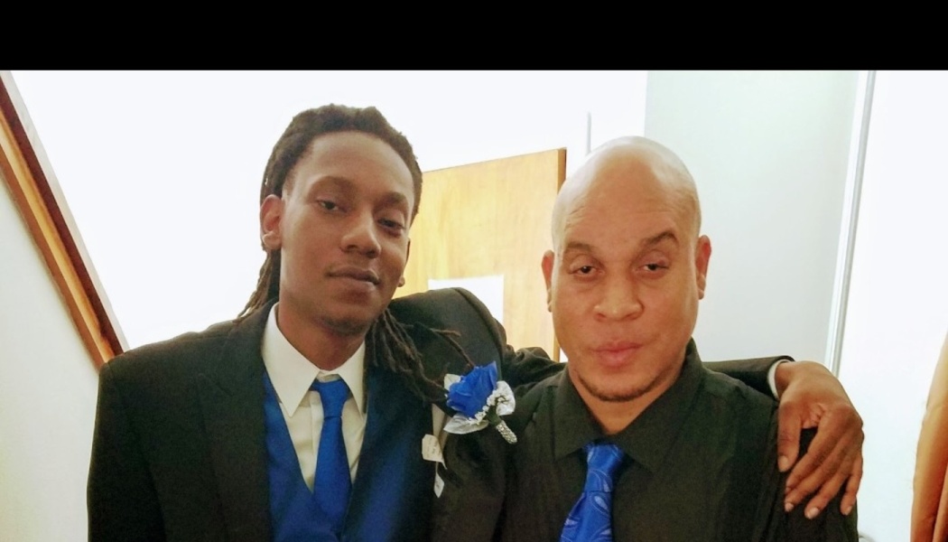 Two men dressed in formal suits with matching blue ties pose together with arms around each other.