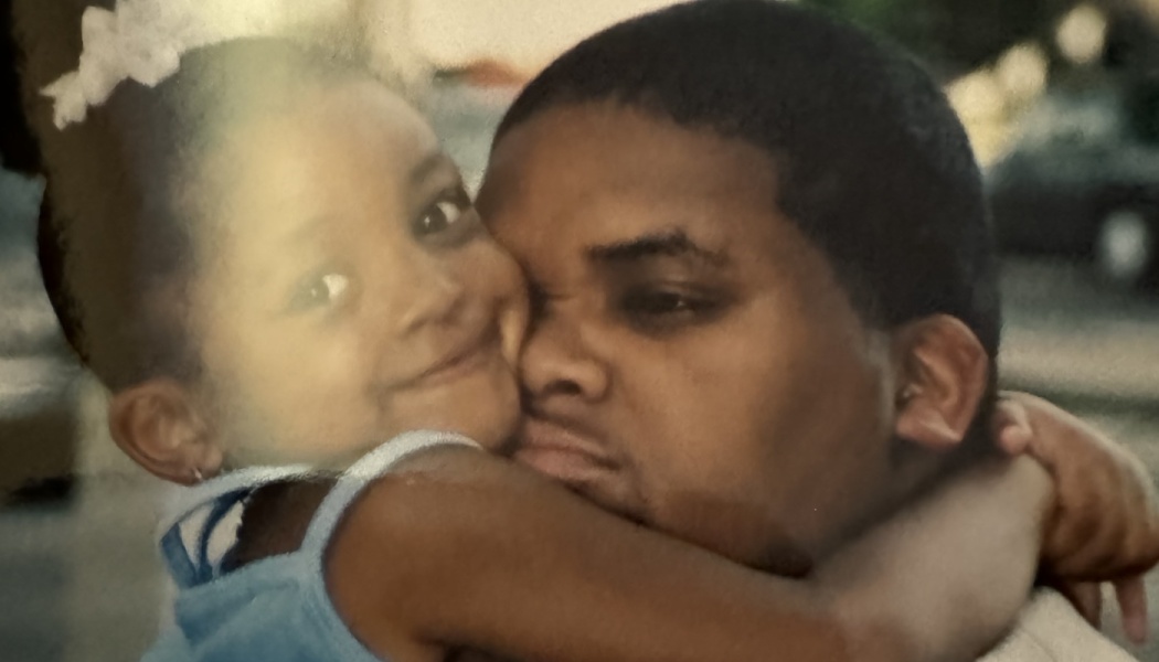 A smiling young girl tightly hugging a man around his neck in a loving embrace.