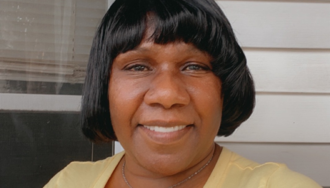 A smiling Black woman with a short black bob haircut wearing a yellow shirt.