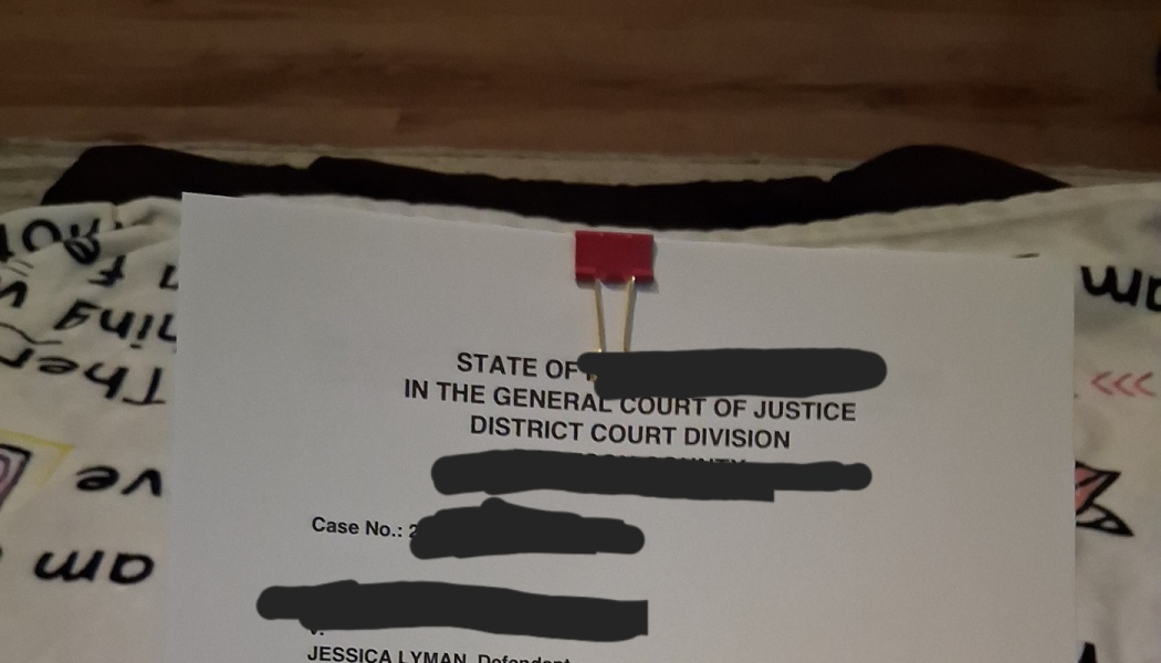 Partially redacted legal court document clipped with a red binder clip at the top.