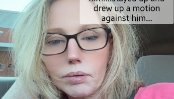 Close-up selfie of a blonde woman with glasses in a car, with text reading "drew up a motion against him..."