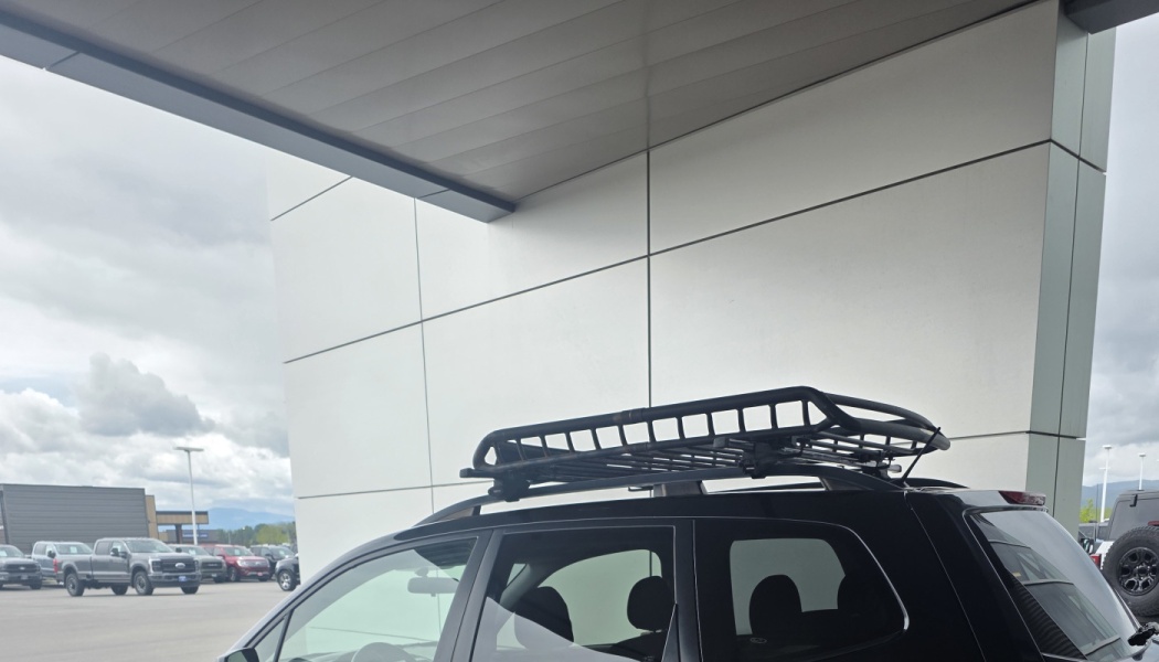 Black roof cargo rack mounted on top of a black SUV parked under a building canopy.