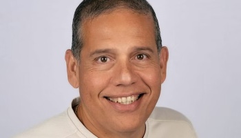 Headshot of a smiling middle-aged man with short hair against a neutral background.