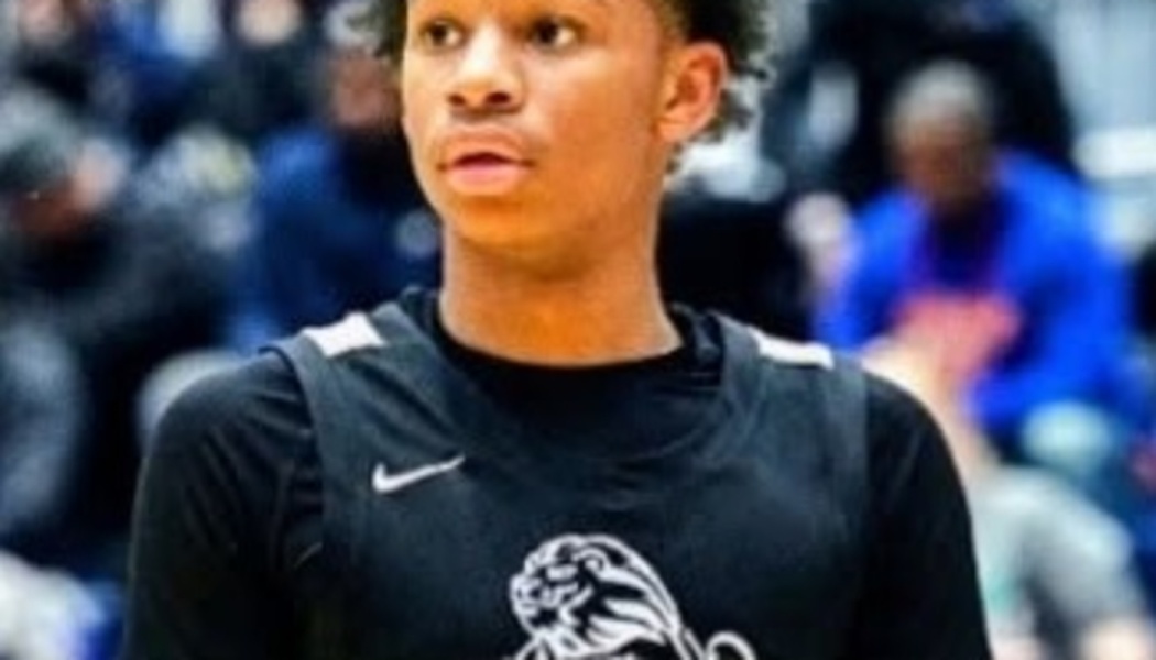 Young male basketball player wearing a black jersey with a lion logo, looking focused on the court.