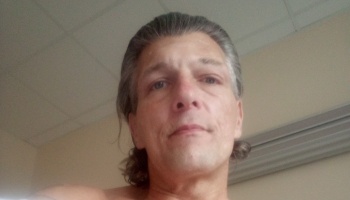 A middle-aged man with salt-and-pepper hair looking down toward the camera.