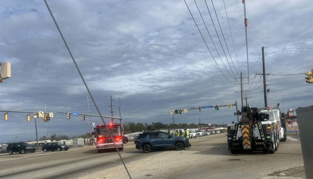 A fire truck and tow truck respond to a car accident involving a damaged blue SUV at an intersection.