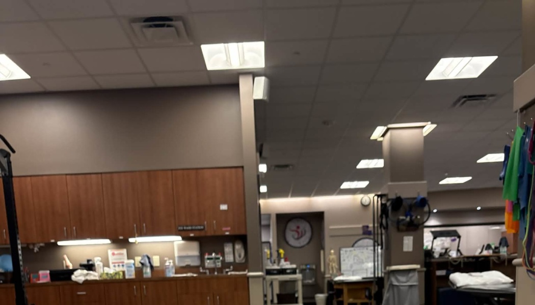 Interior of a physical therapy clinic featuring wooden cabinets, ceiling lights, and exercise equipment.