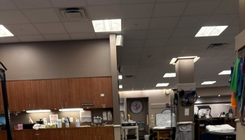 Interior of a physical therapy clinic featuring wooden cabinets, ceiling lights, and exercise equipment.