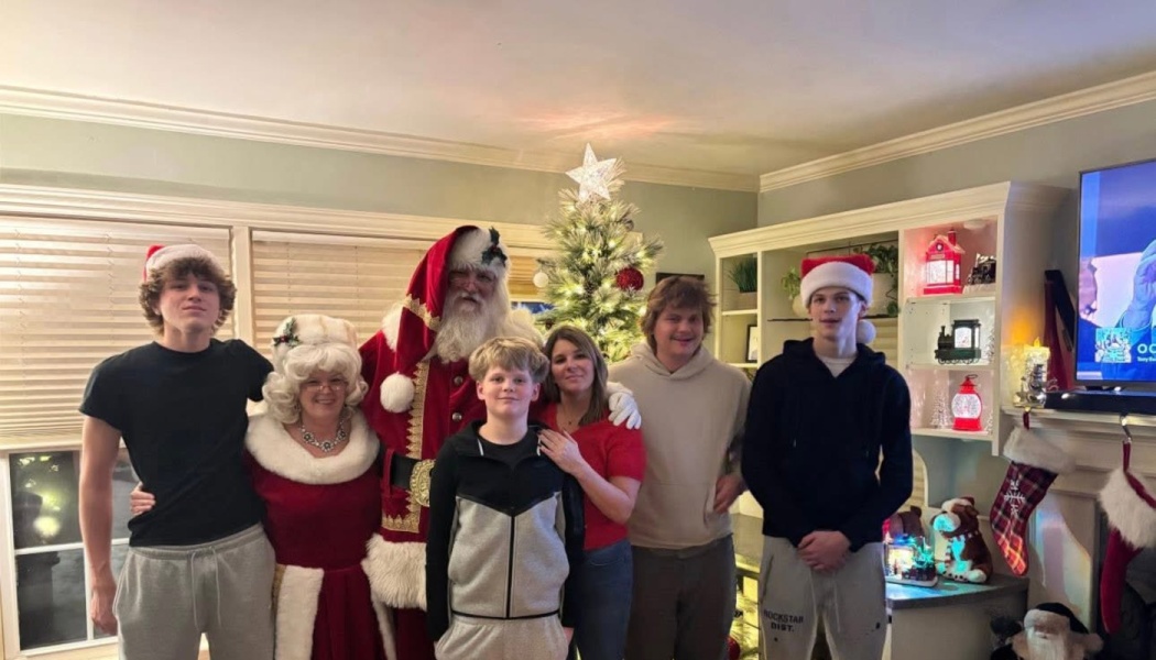 A family poses with Santa Claus and Mrs. Claus in front of a decorated Christmas tree.