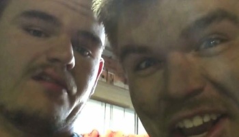 Close-up selfie of two young men looking down into the camera with animated expressions.