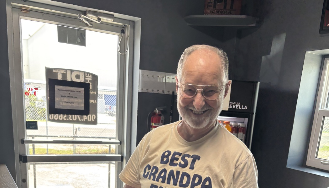 A smiling elderly man with glasses and a beard wearing a Best Grandpa t-shirt.
