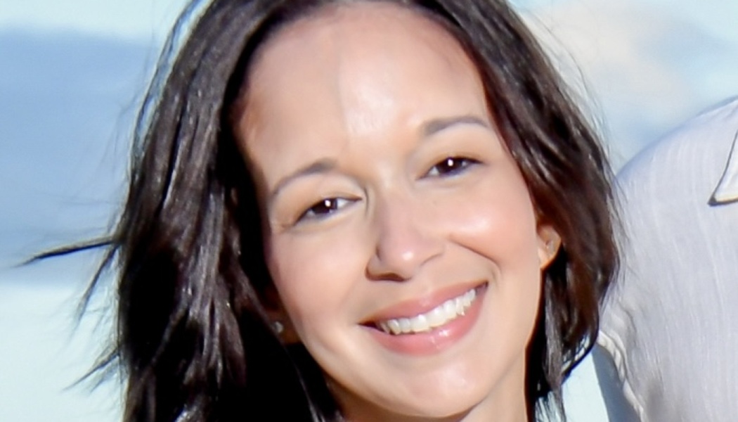 Close-up portrait of a smiling woman with dark brown hair.